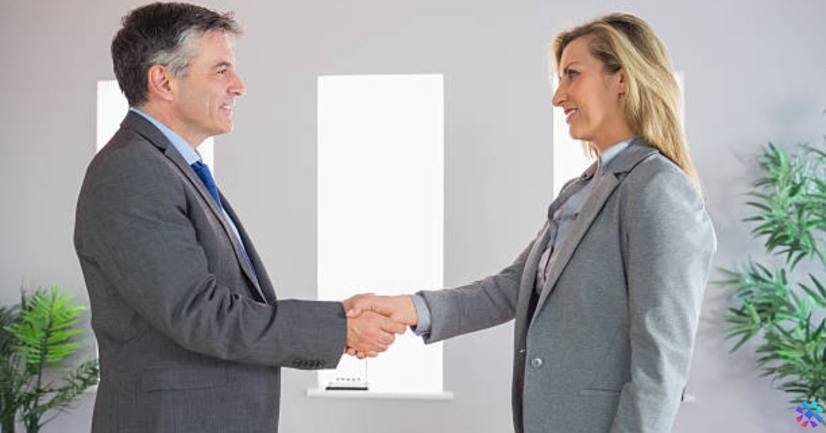 A professional handshake between a man and woman in an office, representing collaboration with Walmart suppliers.